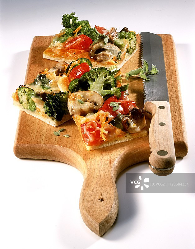 五颜六色的蔬菜披萨，切成小块放在砧板上图片素材