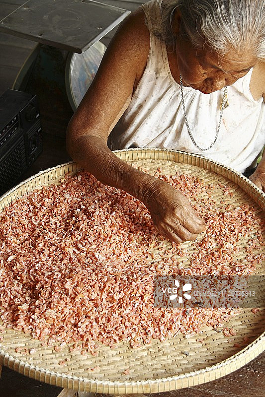 泰国，一位年长的妇女正在分拣虾干图片素材