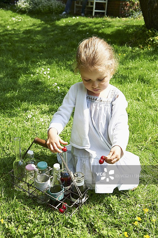一个小女孩在花园里玩樱桃图片素材