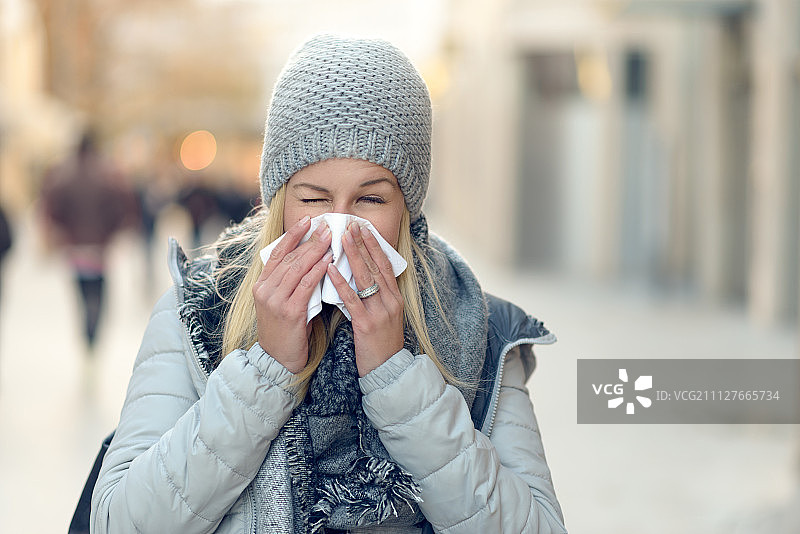患季节性冬季感冒的妇女擤鼻子图片素材