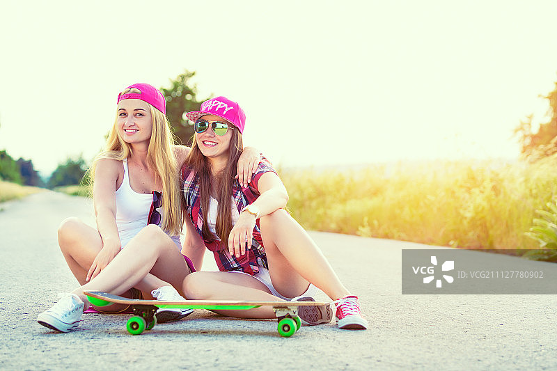 迷人微笑的潮人青少年朋友滑板，彩色图像与太阳耀斑图片素材
