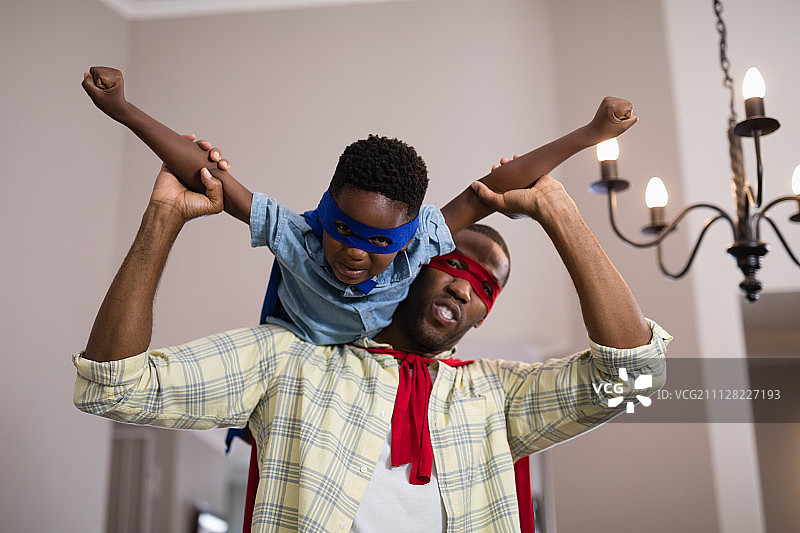 顽皮的父亲和儿子穿着超级英雄的服装在家图片素材