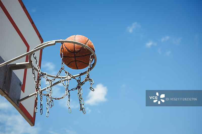 低角度的篮球在篮框对蓝色的天空图片素材