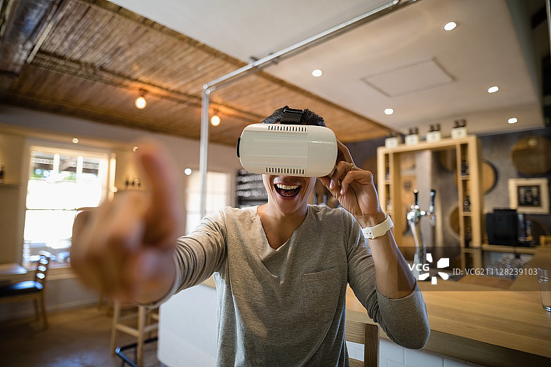 微笑的男人使用虚拟现实耳机在餐厅图片素材