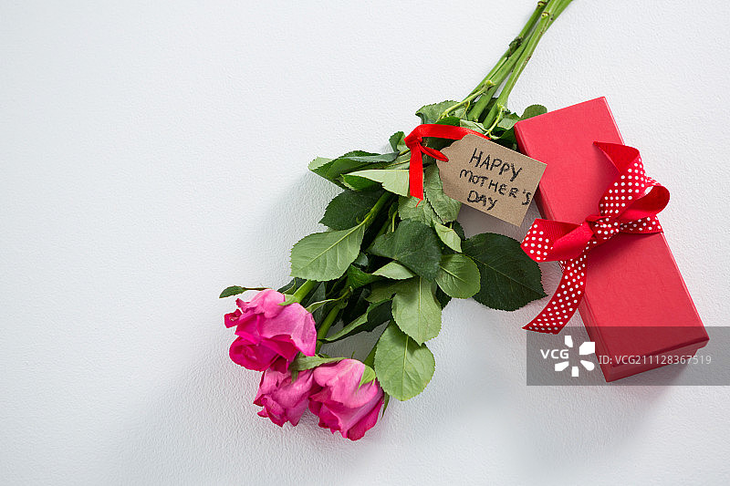 礼物盒和一束粉红色玫瑰与快乐的母亲节标签在白色的背景图片素材
