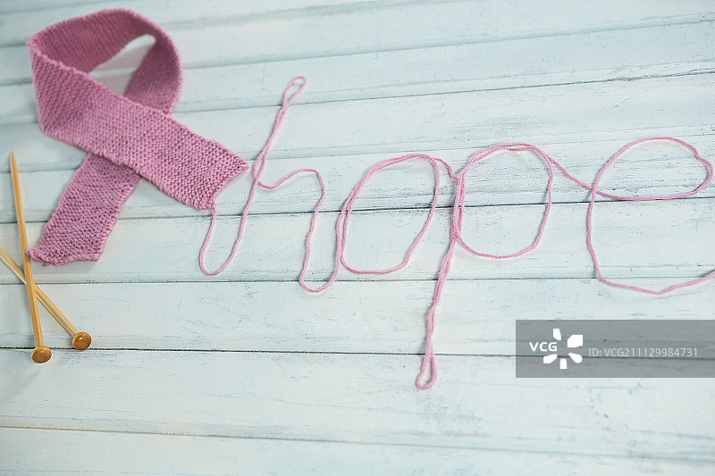 高角度的粉红色乳腺癌意识丝带希望文本和钩针在白色木制桌子上图片素材