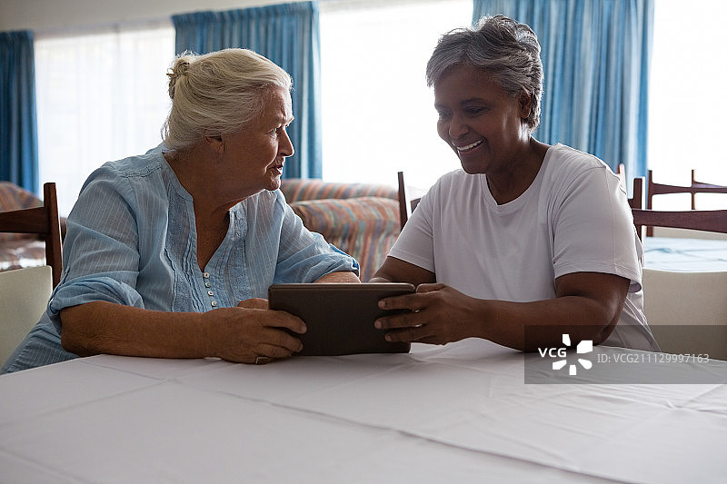 老年妇女在养老院向朋友展示数字平板电脑图片素材
