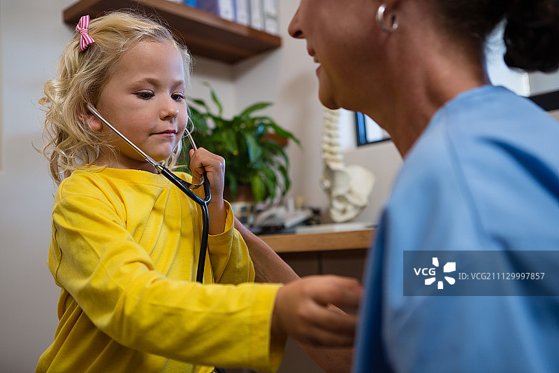可爱的小女孩在医院使用听诊器图片素材