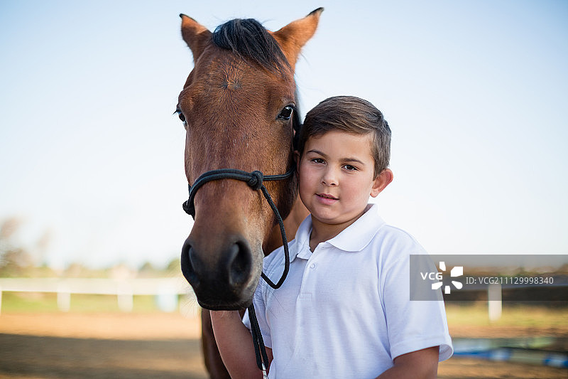 在一个阳光明媚的日子里，骑手男孩在牧场里抚摸着一匹马图片素材