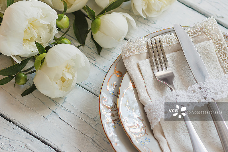 白色木板上放着一束白色牡丹的餐具和银器图片素材