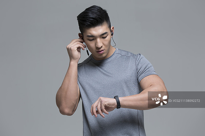 戴耳机的男运动员运动后查看智能手环图片素材