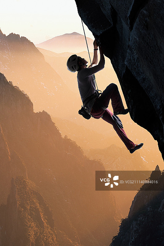 中年男人悬崖上攀岩图片素材