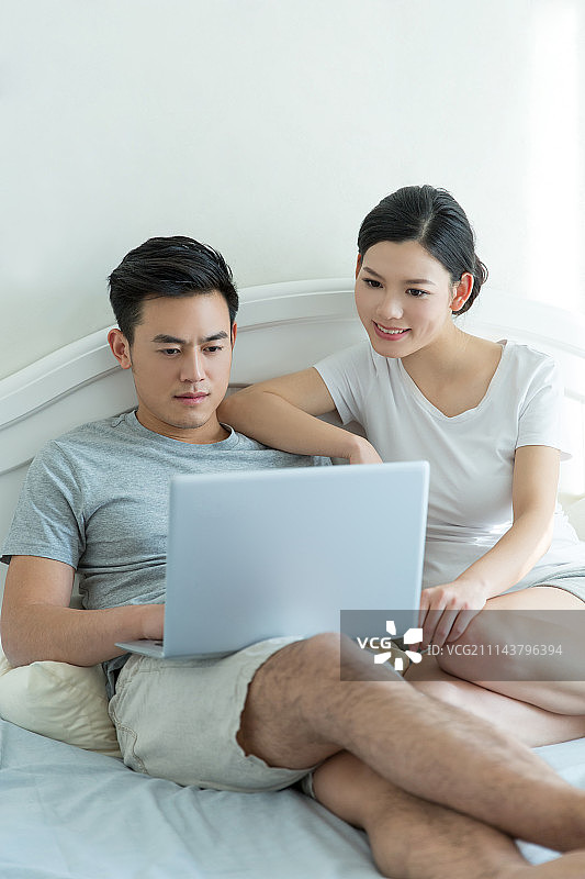 年轻夫妇在床上使用笔记本电脑图片素材