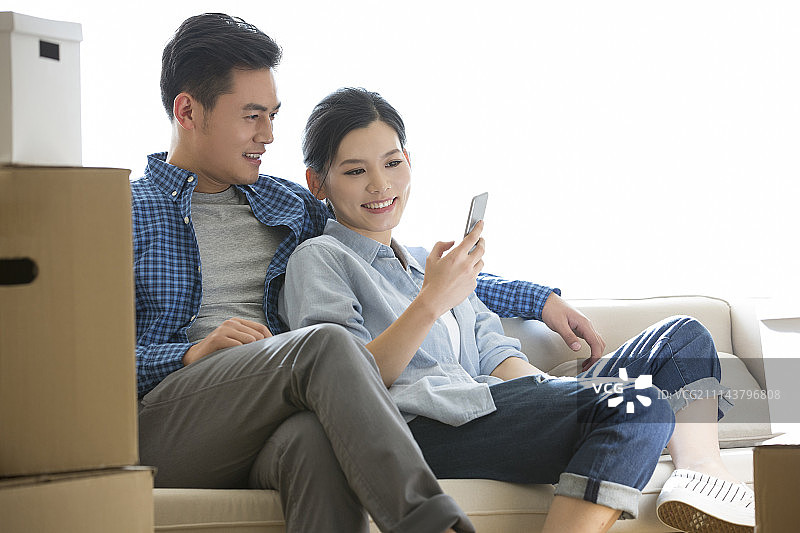 年轻情侣坐在沙发上看手机图片素材