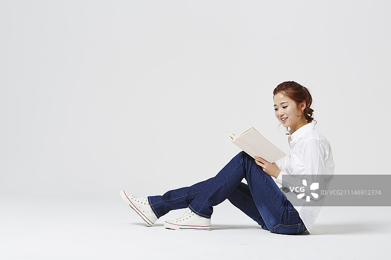 一个女人在白色的背景下读一本孤立的书图片素材