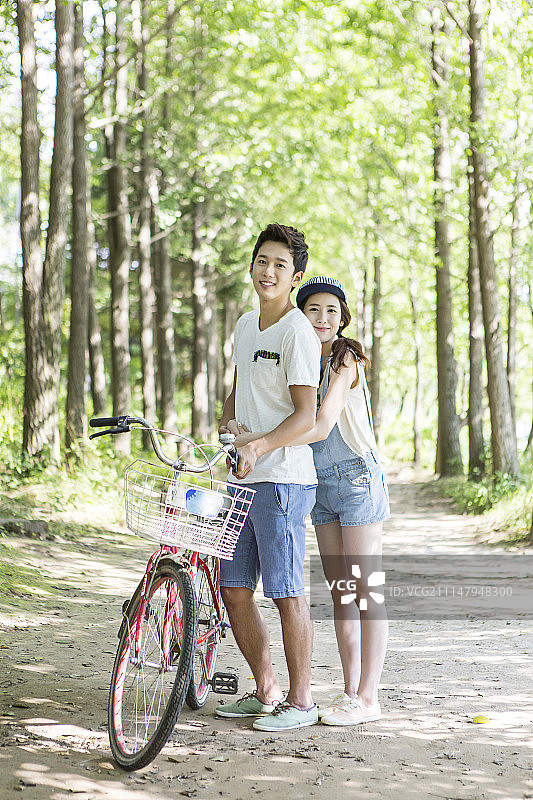 在公园里，一对情侣站在自行车旁边图片素材