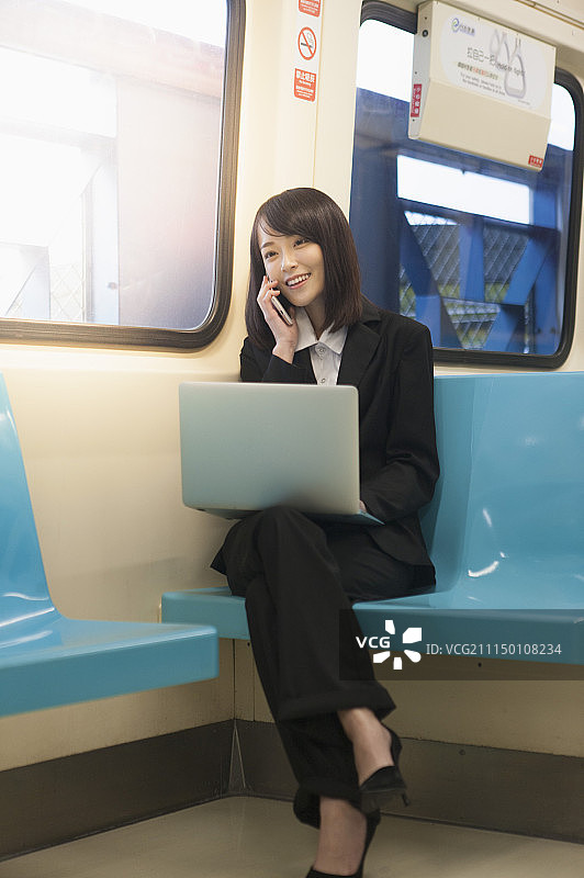 一位办公女性搭乘捷运时打电话图片素材
