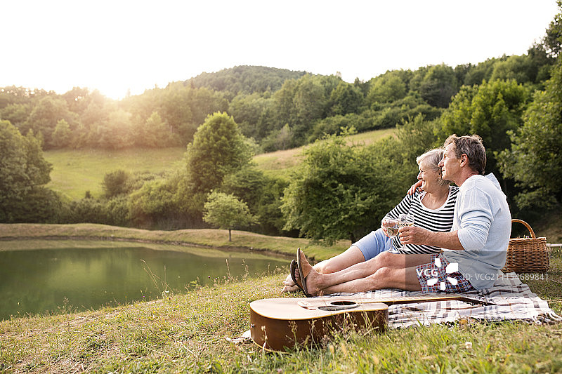 一对老年夫妇在湖边野餐。图片素材