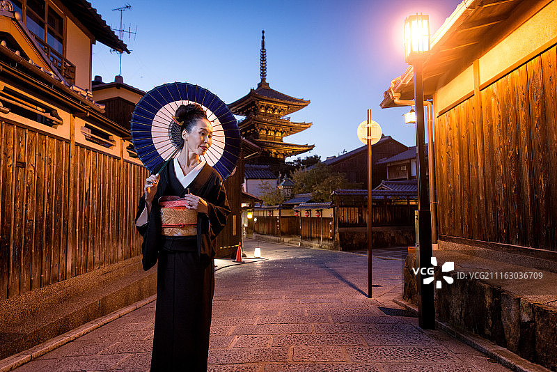 穿着和服和雨伞的日本妇女在古老的日本城镇的街道上图片素材