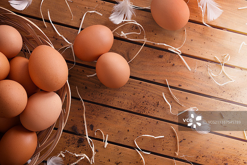 新鲜采摘的鸡蛋在篮子上的木头桌子顶视图图片素材