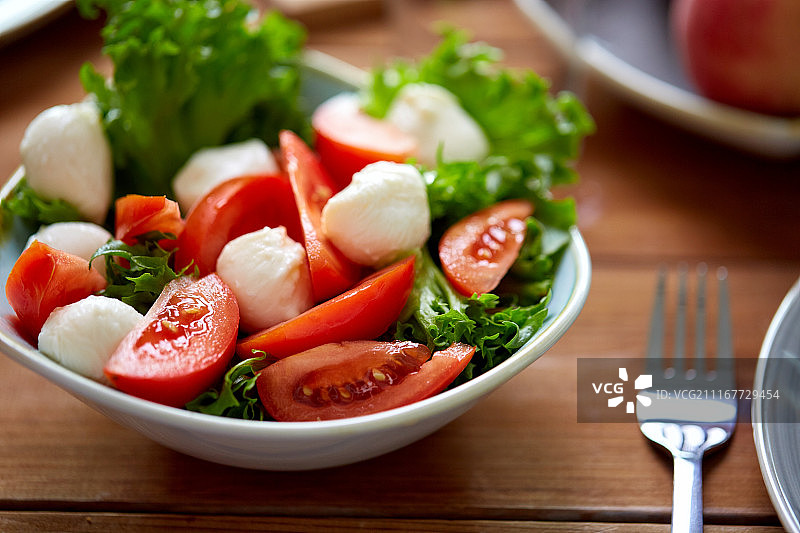 健康饮食，素食和烹饪理念-接近蔬菜沙拉番茄和马苏里拉奶酪在桌子上。最后是马苏里拉奶酪蔬菜沙拉图片素材