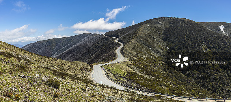一条柏油路蜿蜒穿过荒山，蓝天图片素材