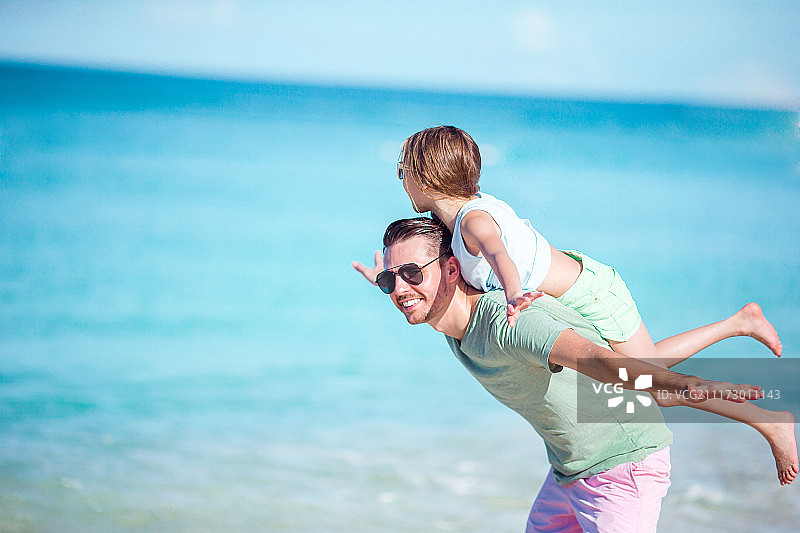 小女孩和快乐的爸爸在海滩度假的乐趣图片素材