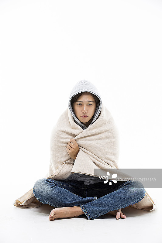 裹在毯子里的年轻男性看起来生病了图片素材