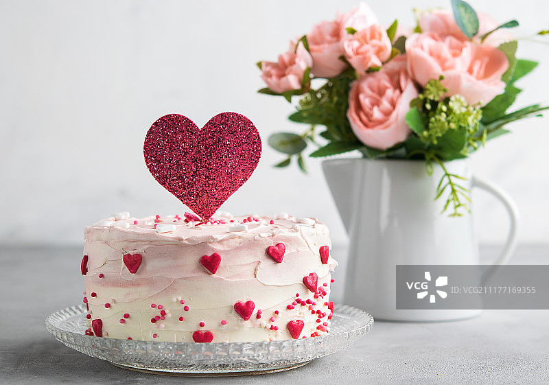 一个蛋糕的近景装饰小的心与心蛋糕顶，反对一个灰色的背景图片素材
