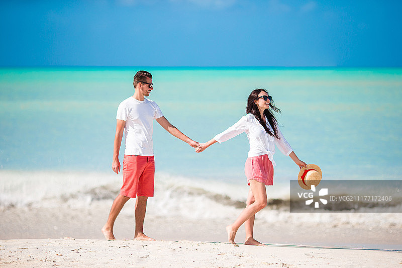 在白色沙滩上的年轻夫妇幸福的家庭在蜜月假期图片素材