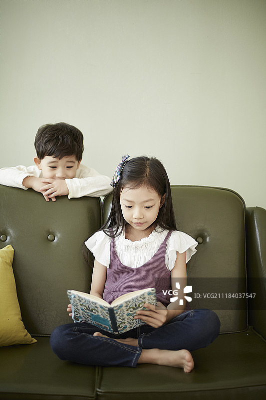 小男孩和小女孩在沙发上看书图片素材