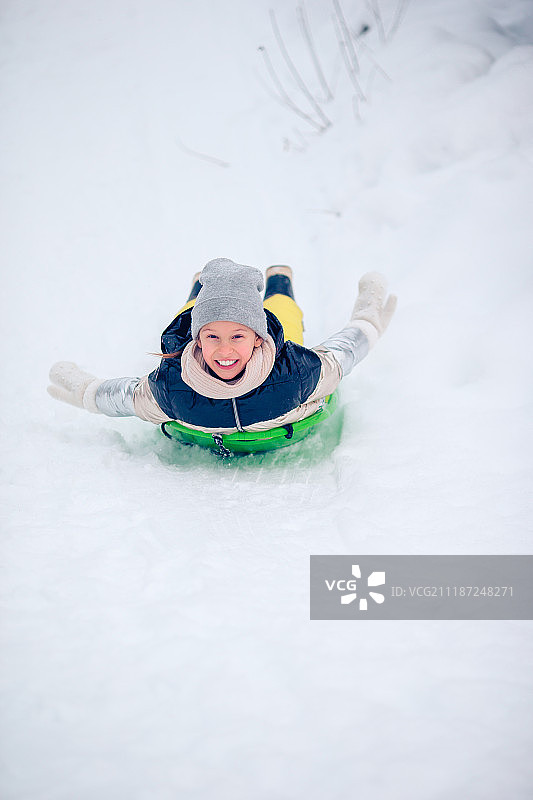可爱的快乐小女孩在冬天下雪的雪橇图片素材