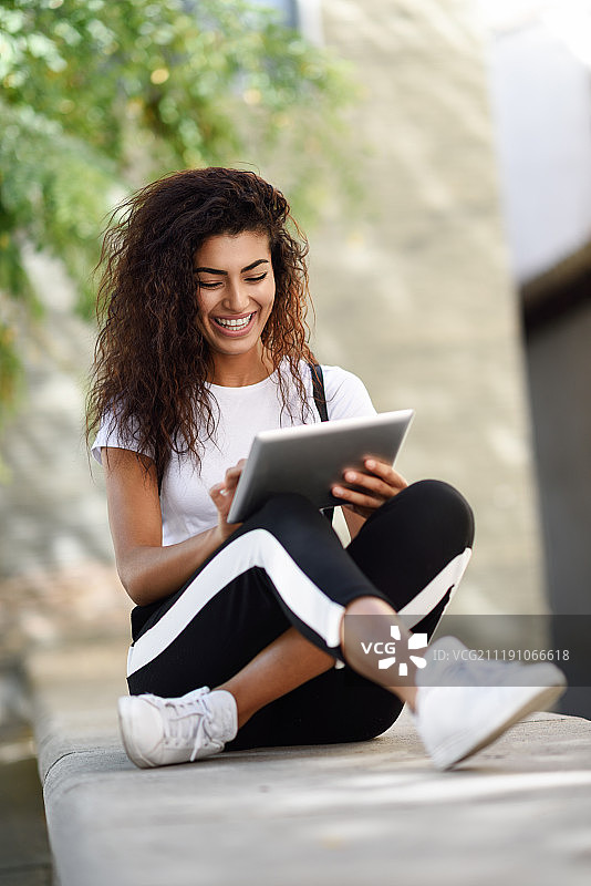 年轻黑人女性穿着运动服在户外使用数字平板电脑图片素材