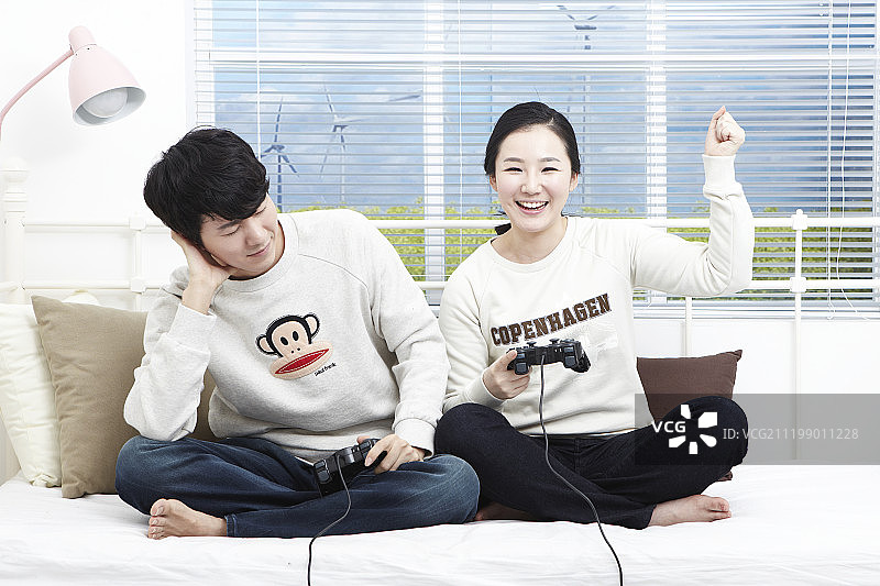 新婚夫妇坐在沙发上玩游戏机图片素材