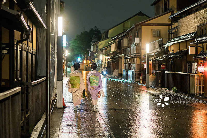 夜晚，两名穿着和服的日本艺伎走在京都的花见小路上图片素材