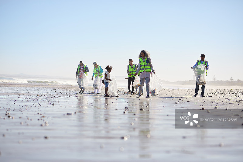 志愿者在阳光明媚的沙滩上清理垃圾图片素材