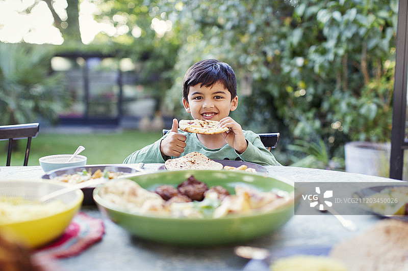 肖像快乐的男孩吃烤饼在露台桌子上图片素材