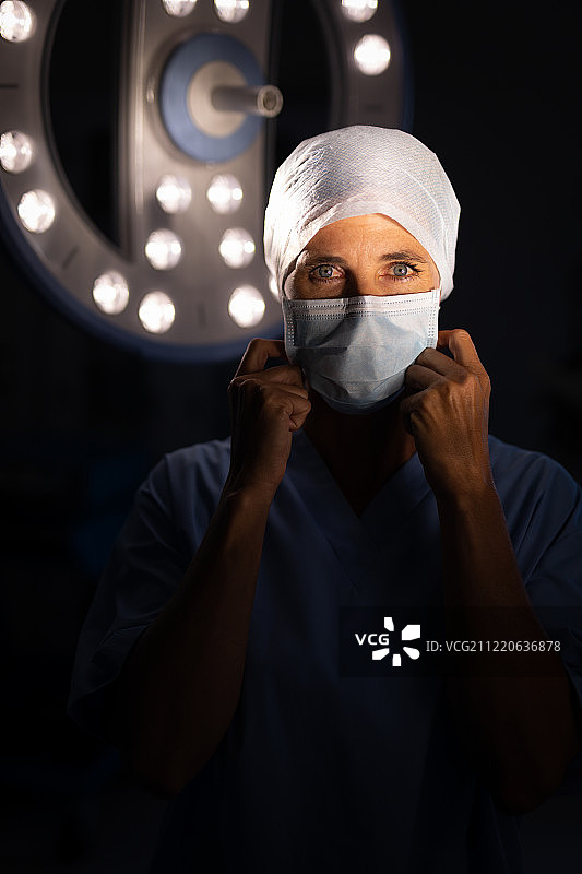 一位白种女外科医生戴着手术口罩，看着医院手术室里的摄像机图片素材