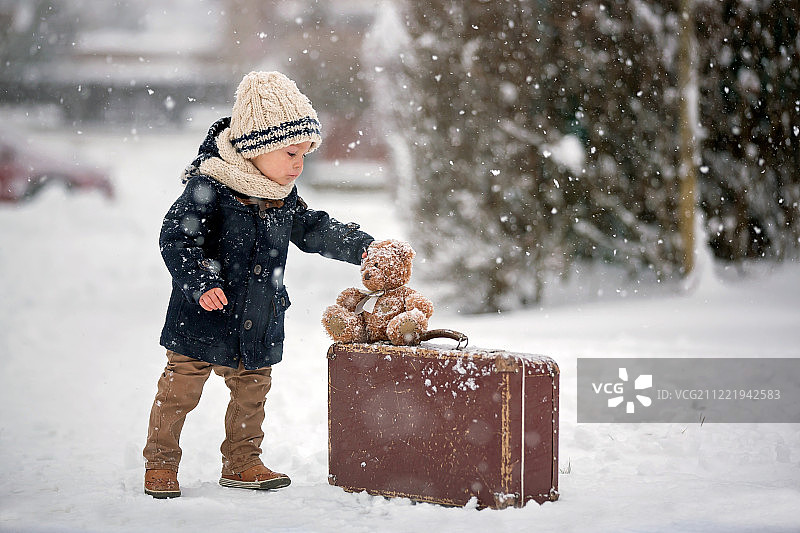 宝宝在雪地里玩泰迪熊，冬天的时候。小的孩子图片素材