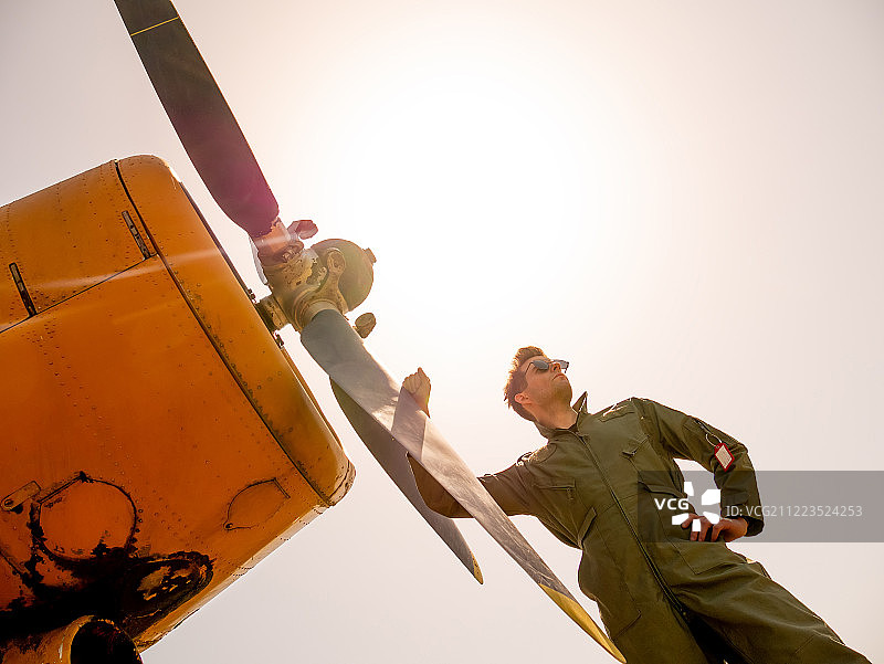一个英俊的年轻飞行员站在螺旋桨旁边图片素材