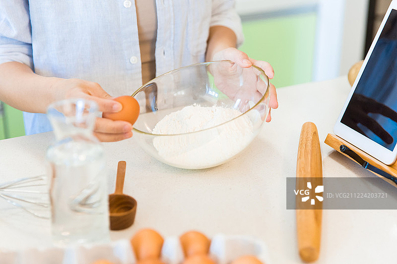 女子在厨房往面粉打鸡蛋准备和面手部特写图片素材