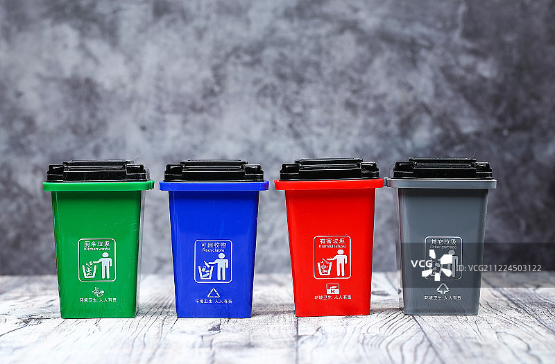 垃圾分类概念 彩色垃圾桶放在灰色木板背景前图片素材
