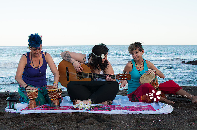 三个年轻女人在大卡纳里亚的拉斯帕尔马斯海滩上玩耍图片素材