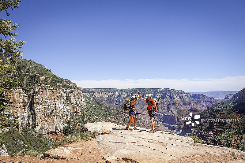 两名女性徒步者在完成陡峭的爬出美国亚利桑那州大峡谷后击掌庆祝图片素材