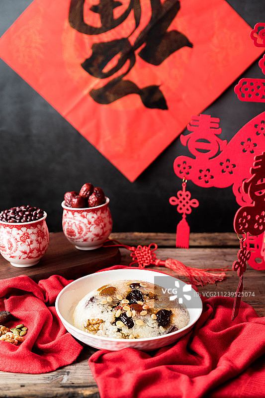 木桌上的放着中国传统美食八宝饭红豆红枣和春节福字图片素材
