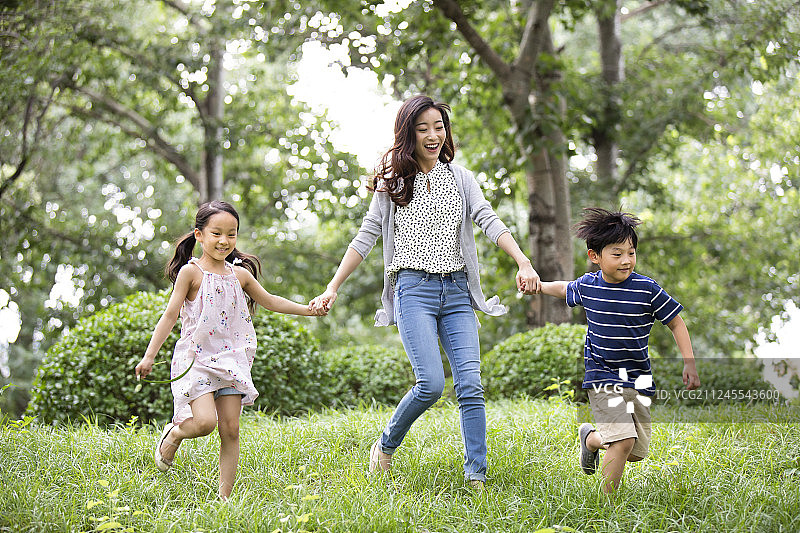 快乐的年轻家庭在草地上奔跑图片素材