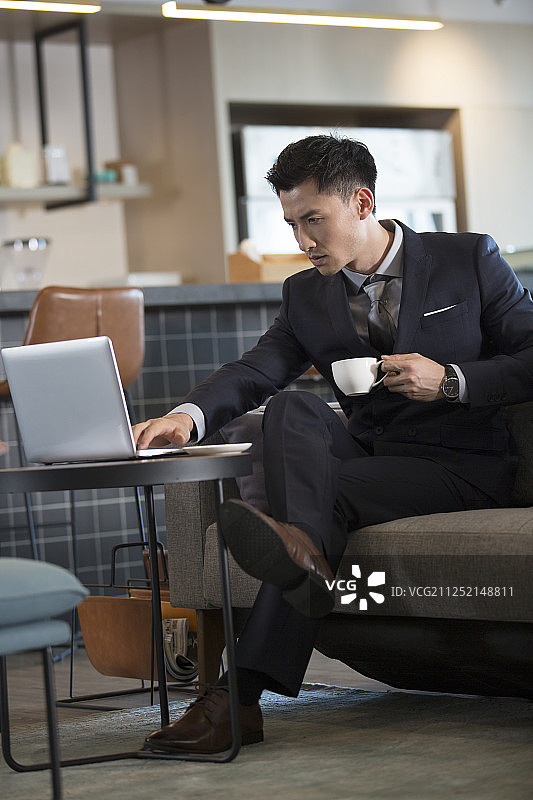 青年商务男子在咖啡馆喝咖啡使用笔记本电脑工作图片素材