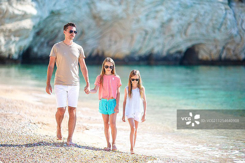 爸爸和孩子们在白色沙滩上的幸福美丽的家庭图片素材