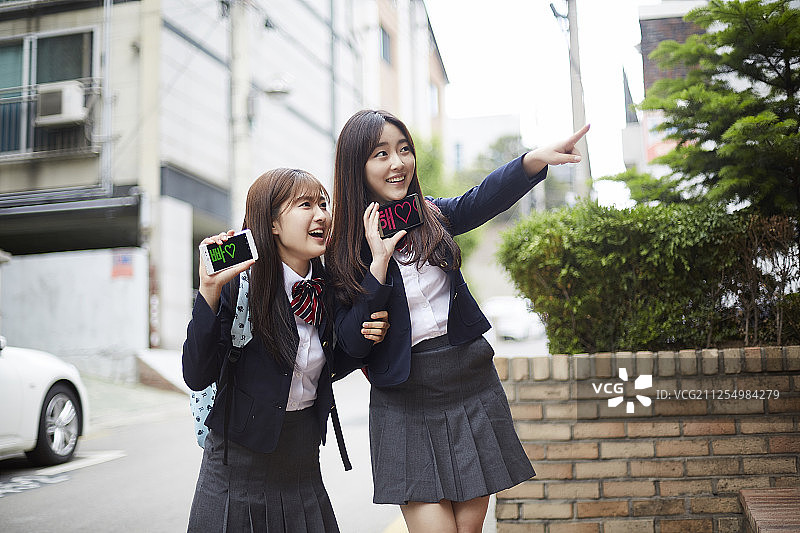 两个少女拿着智能手机等待的照片图片素材