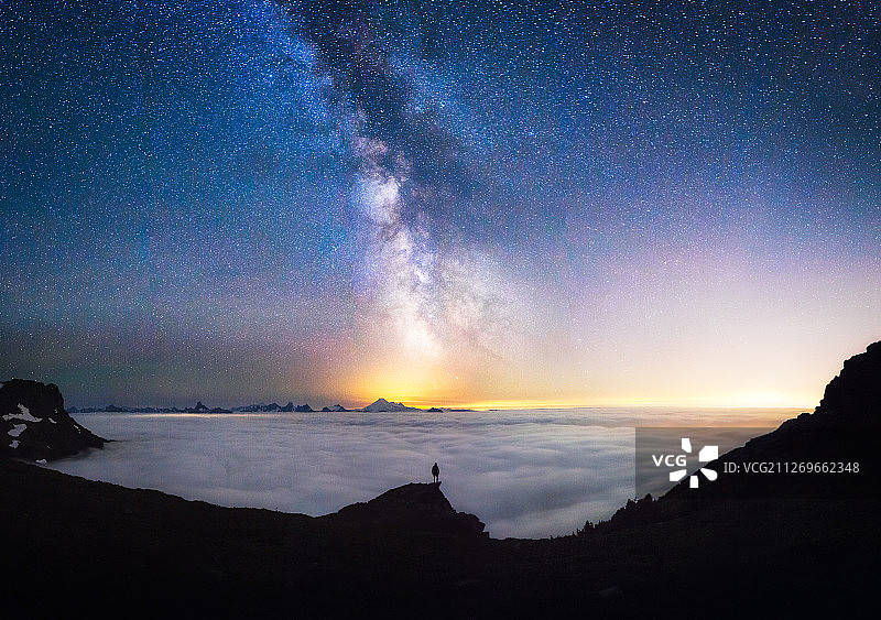 一个人站在云霄之上，仰望天空中的银河图片素材